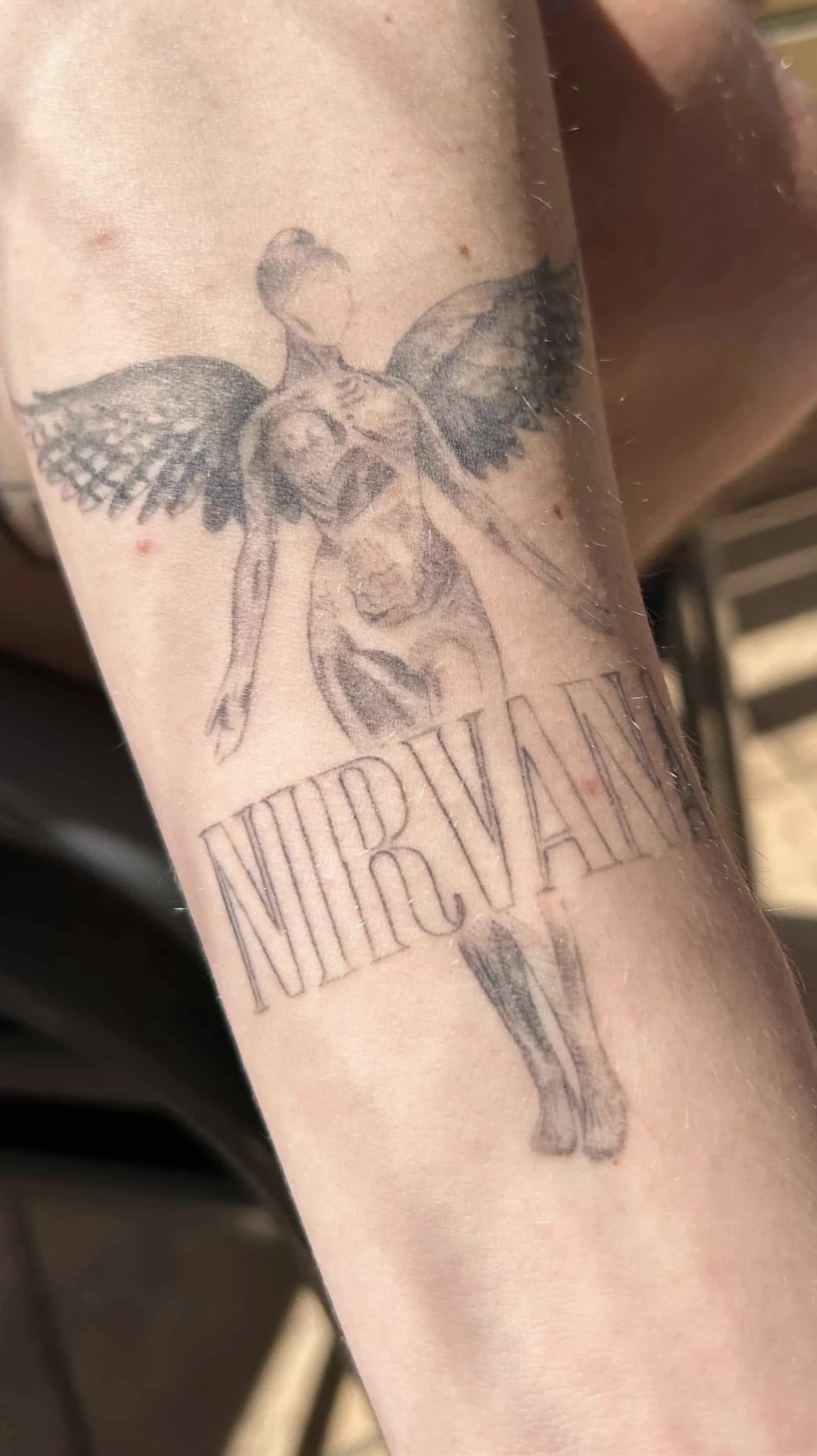 Nahaufnahme eines Unterarm-Tattoos mit NIRVANA Cover Motiv