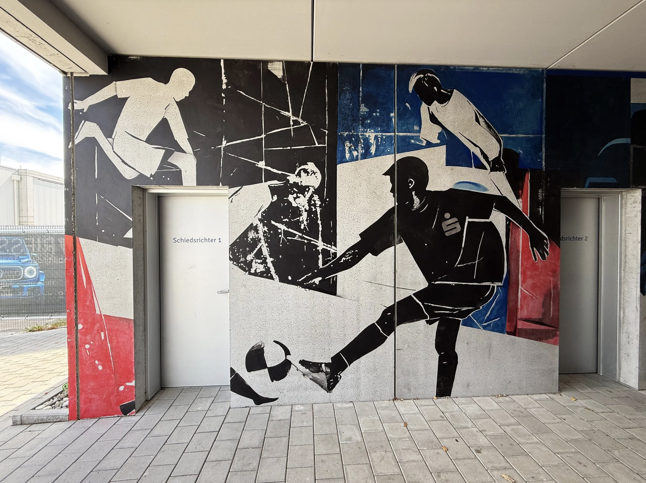 Streetkunst auf einer Wand zeigt eine schwarze Silhouette eines Mannes, der mit einem Fußball spielt.