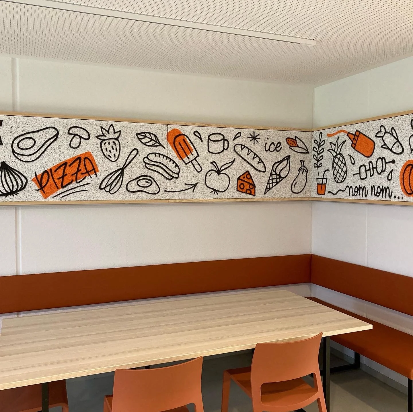 Eine Wand mit handgezeichneten Lebensmittel- und Getränkeillustrationen, darunter Pizza, Eis, Obst, Kuchen und Getränke. Das Wort 'Pizza' ist hervorgehoben. Es gibt auch einige deutsche Wörter wie 'nom nom'.
