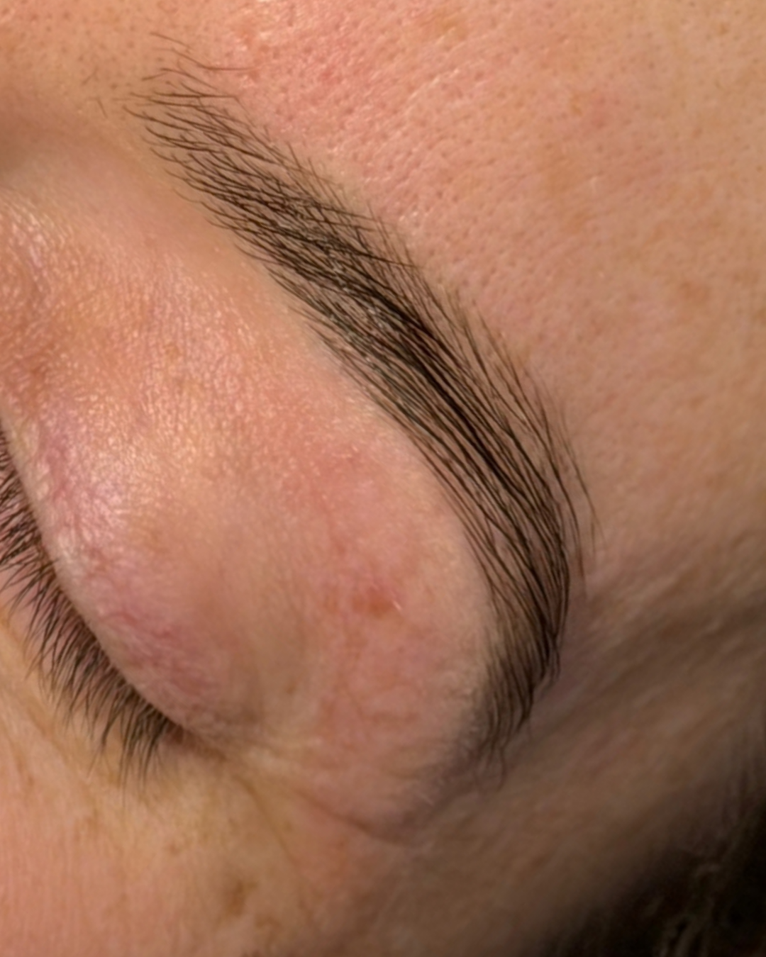Close-up of a person’s closed eye, eyebrow, eyelashes, and surrounding skin