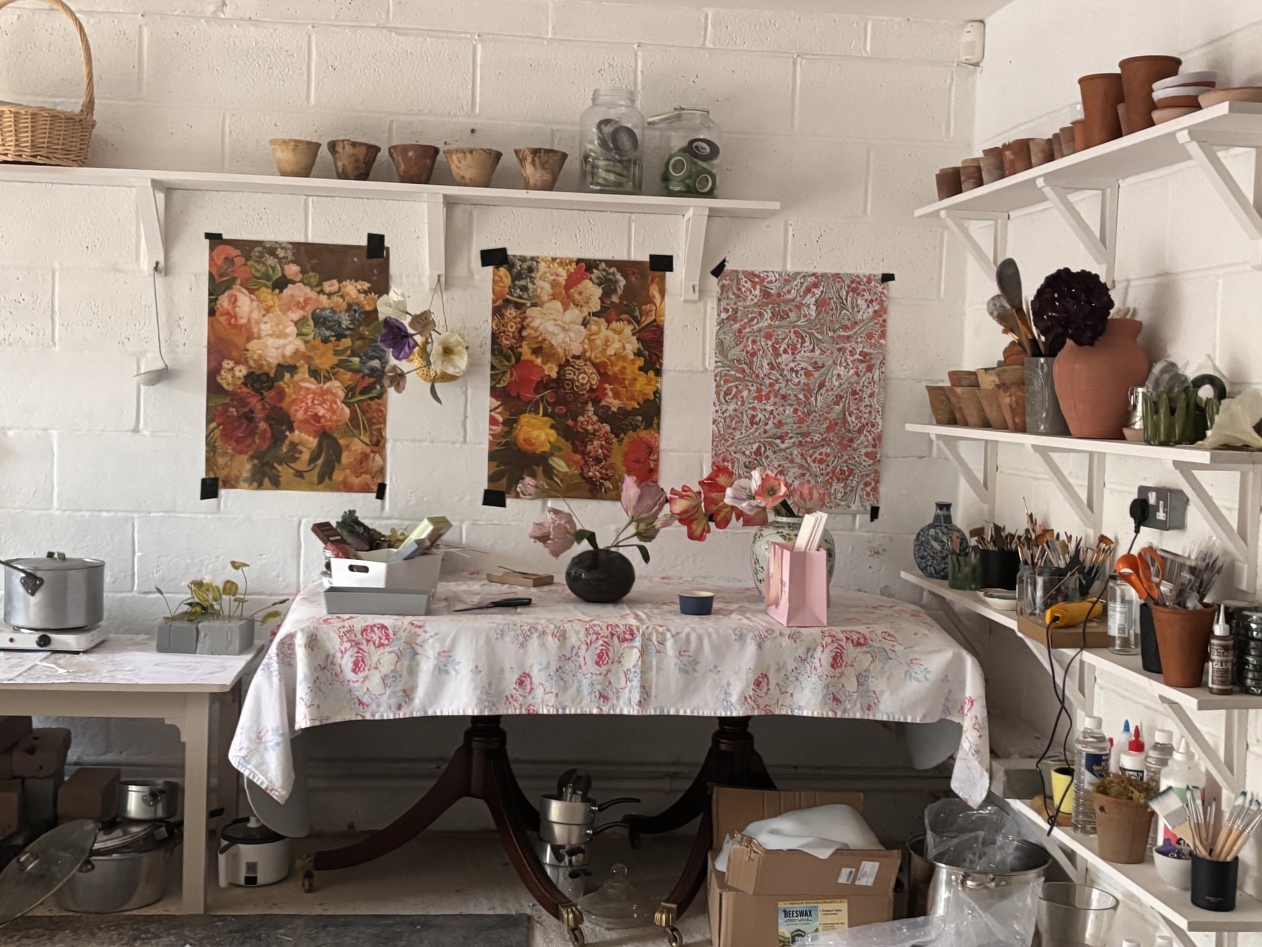 Cultivating flowers and plants in a workshop or studio with shelves holding pots, jars, and gardening tools.