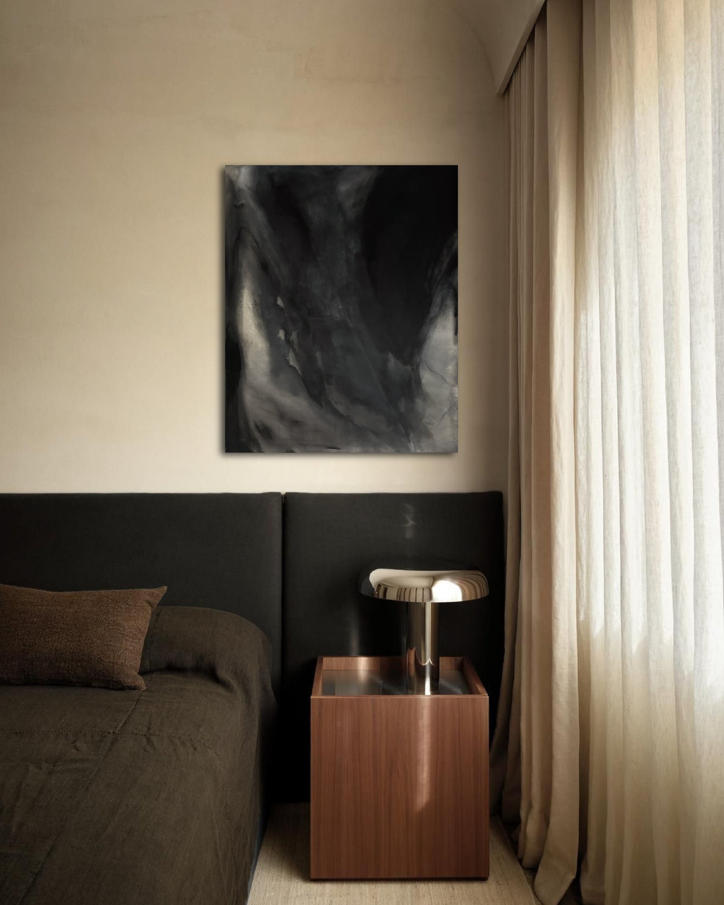 Modern bedroom with a dark upholstered bed, abstract wall art, wood nightstand, black lamp, and sheer curtains.