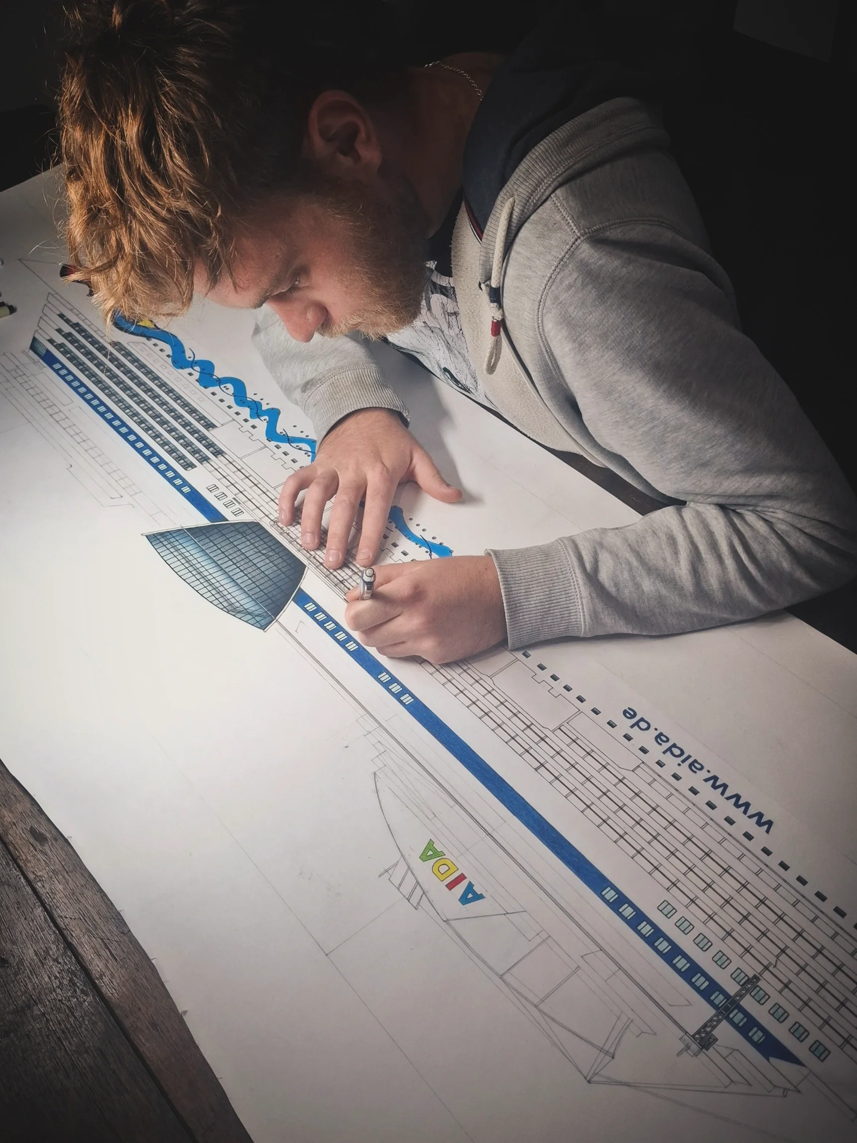 A person working on engineering architectural plans and blueprints on a desk, with a focus on drawing details.