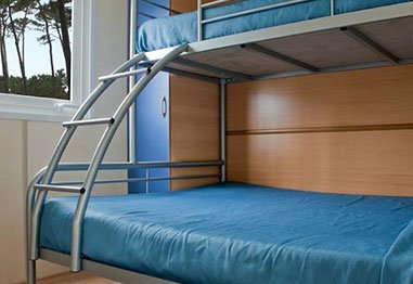 Blue bunk bed with a curved metal ladder in a bedroom