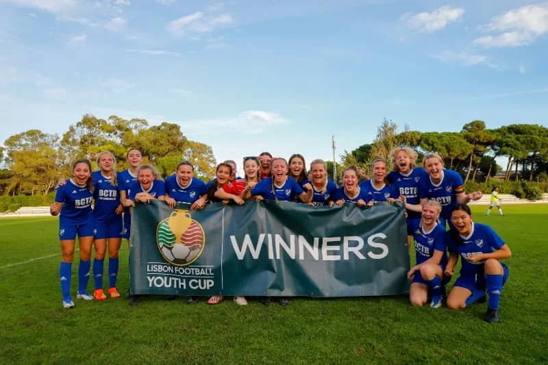 Youth soccer team celebrating as Lisbon Football Youth Cup winners behind a championship banner