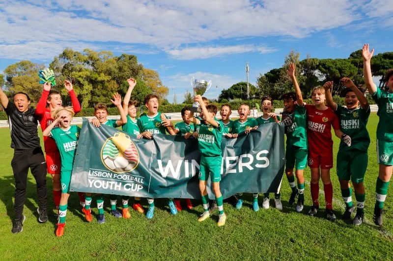 Celebrating youth soccer team holding a trophy and winners banner at the Lisbon Football Youth Cup