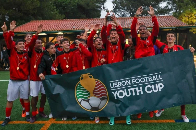 Celebrating youth soccer team holding a trophy and Lisbon Football Youth Cup banner