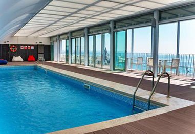 Indoor swimming pool with ocean views through floor-to-ceiling windows