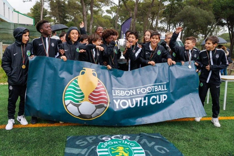 Sporting CP youth soccer team celebrating behind a Lisbon Football Youth Cup banner