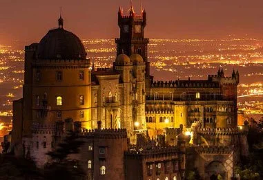 Illuminated historic castle overlooking a city at night
