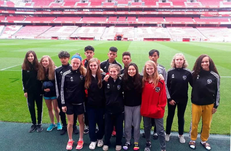 Youth soccer team posing on the field inside a large red-and-white stadium