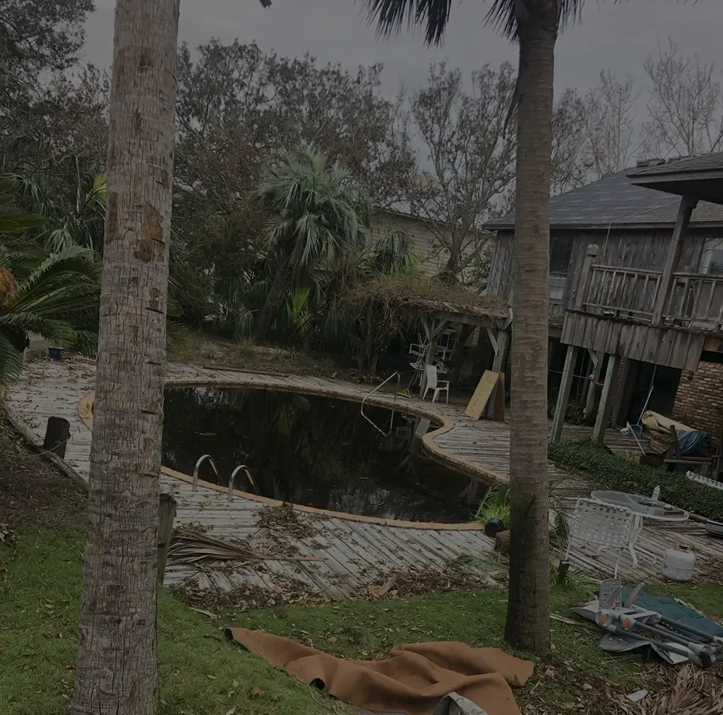 Backyard with a small swimming pool, palm trees, wooden deck, and raised wooden house