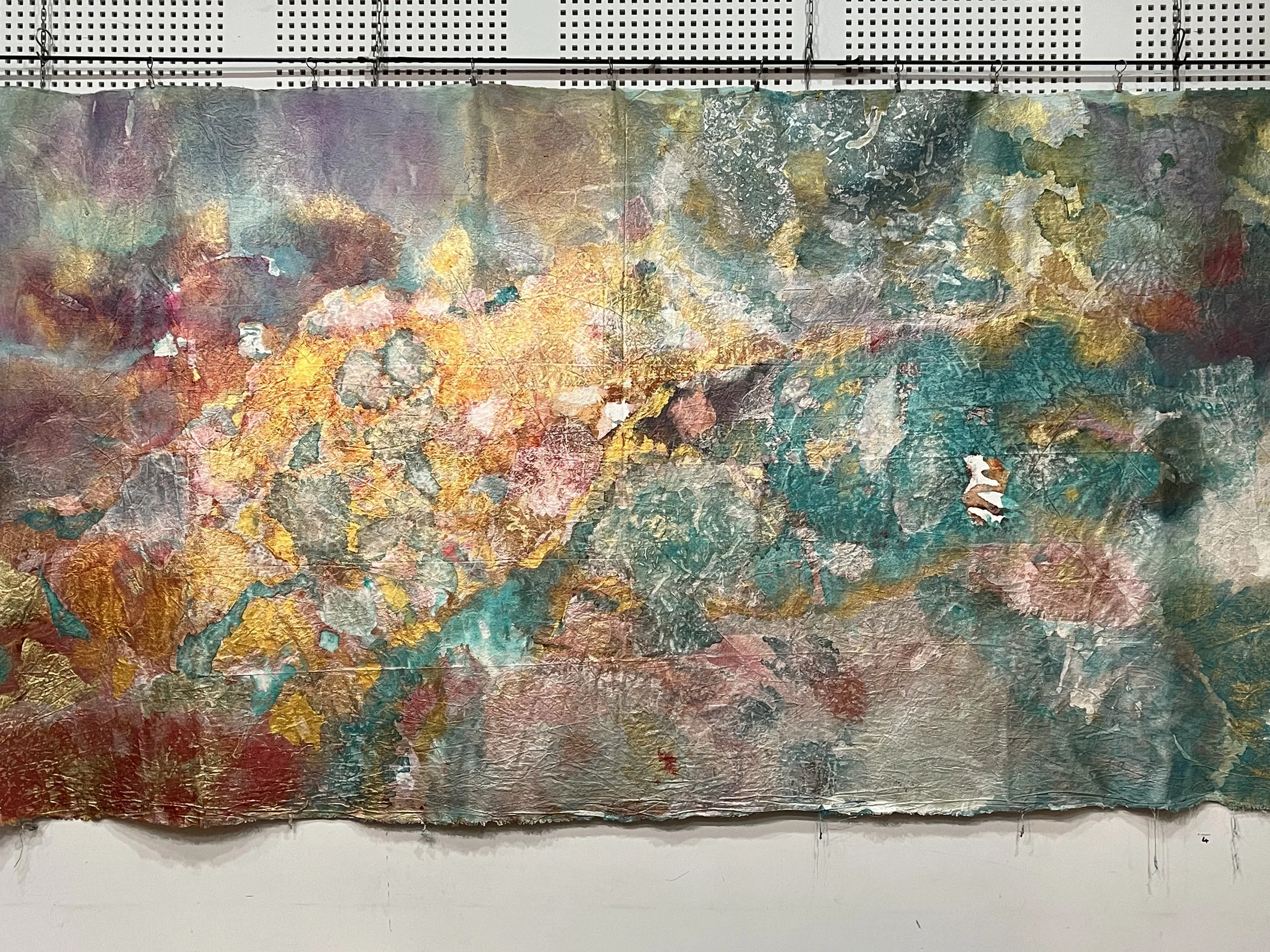 Une peinture abstraite colorée avec des textures riches et des motifs variés, exposée dans une galerie.
