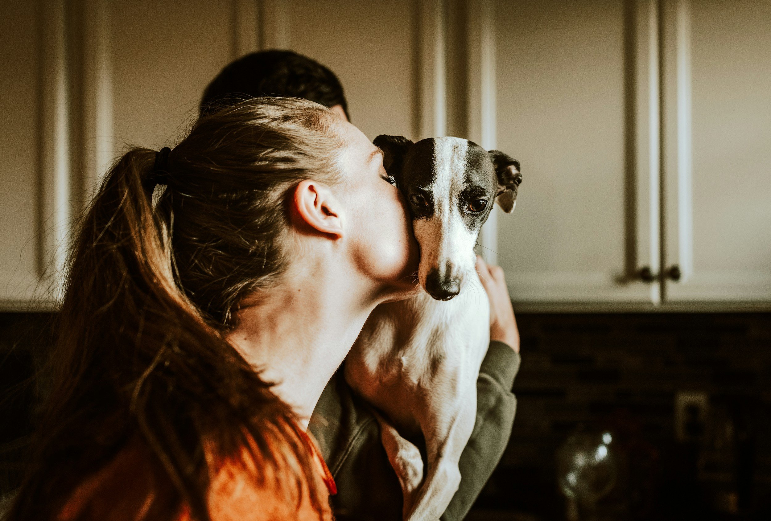 Frau umarmt einen schwarz-weißen Hund vor einem Kamin