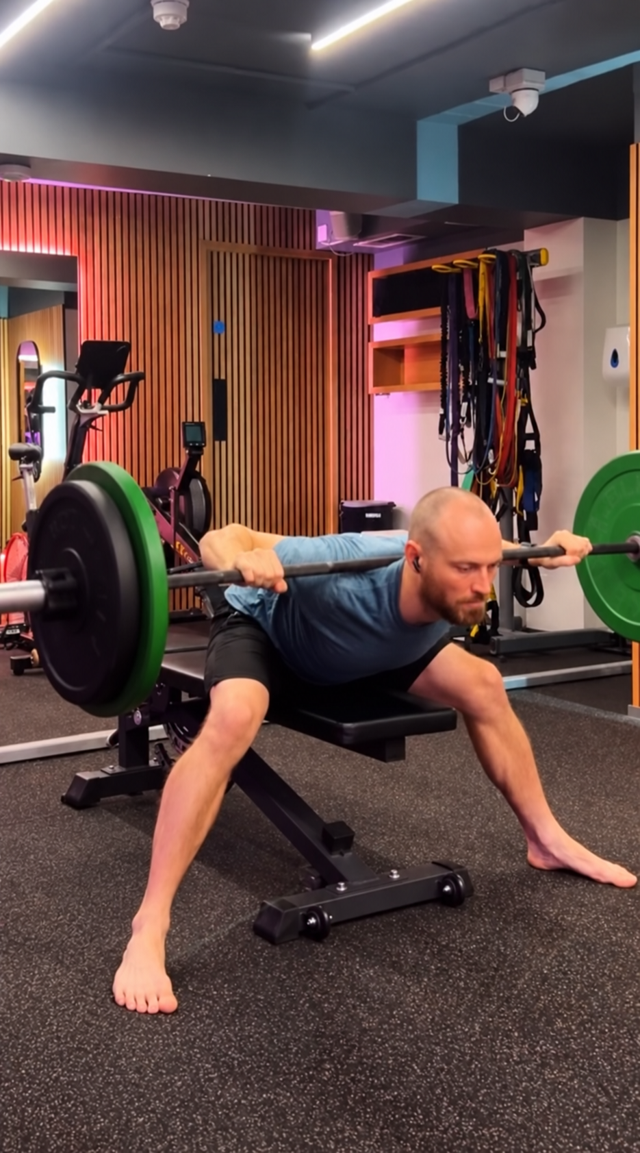 A man performing a barbell squat exercise in a gym, with weight plates on the barbell.