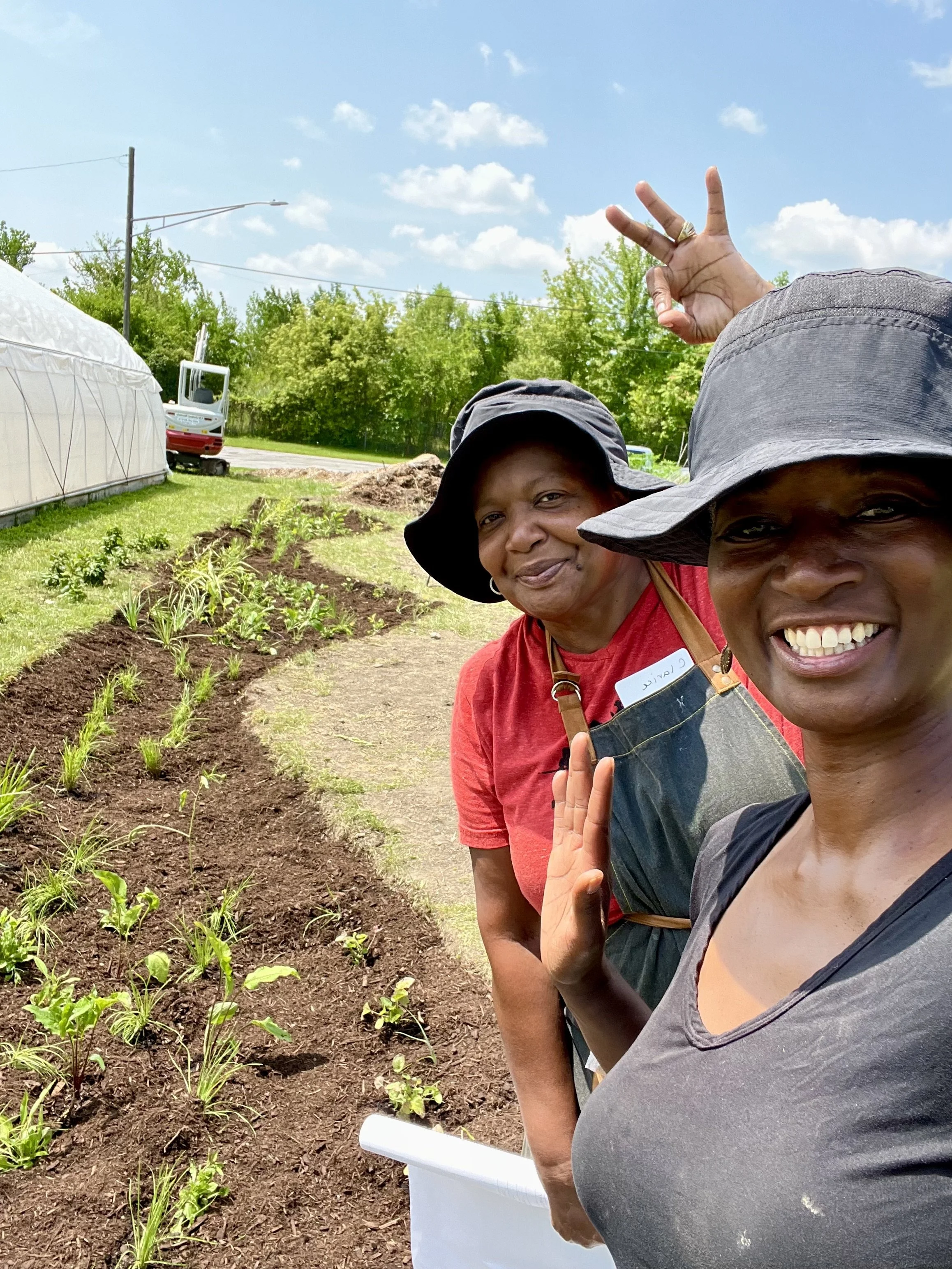 Two people smiling next to a curving garden bed