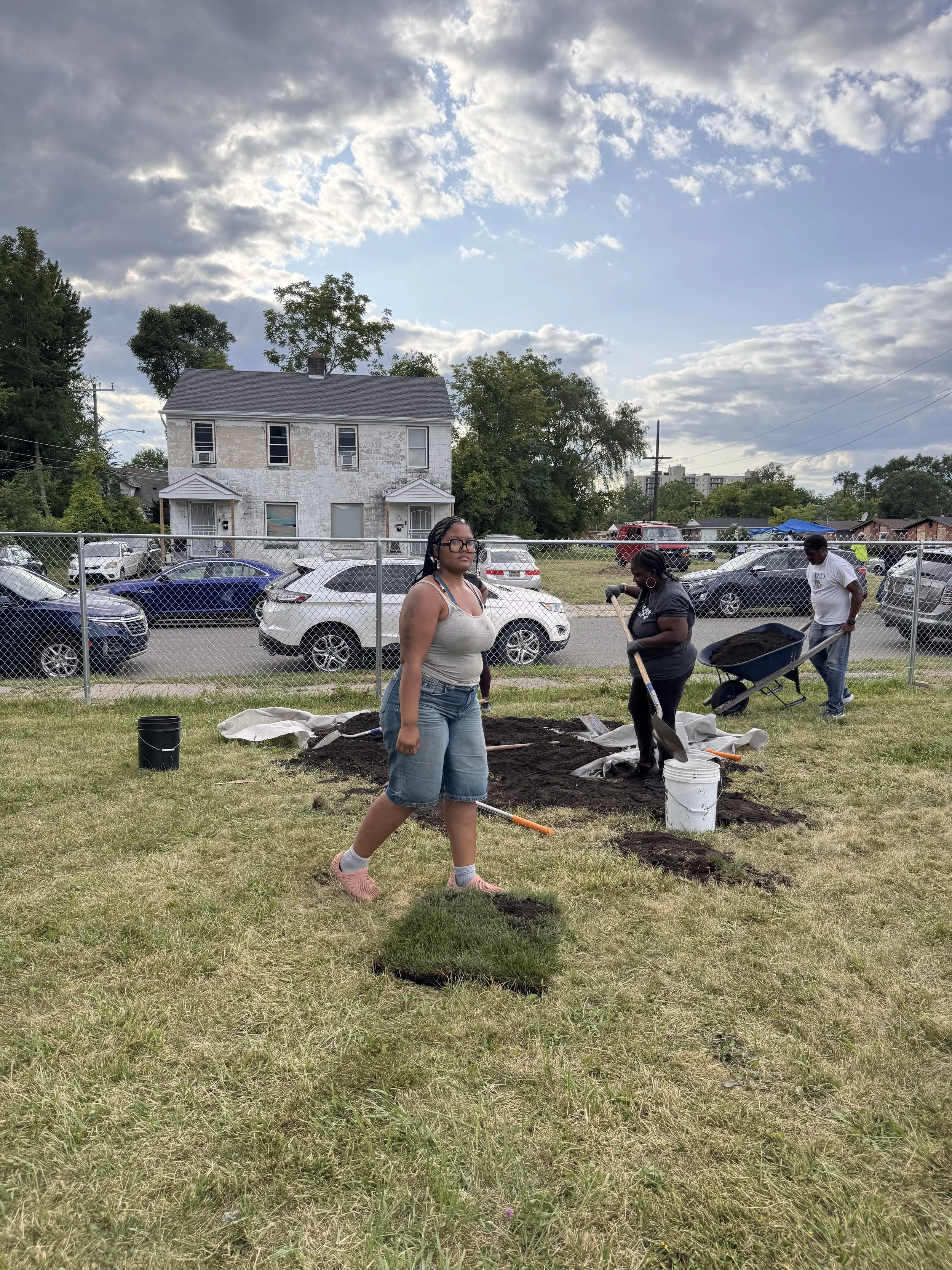 Three people shoveling compost at an urban garden in Southwest Detroit