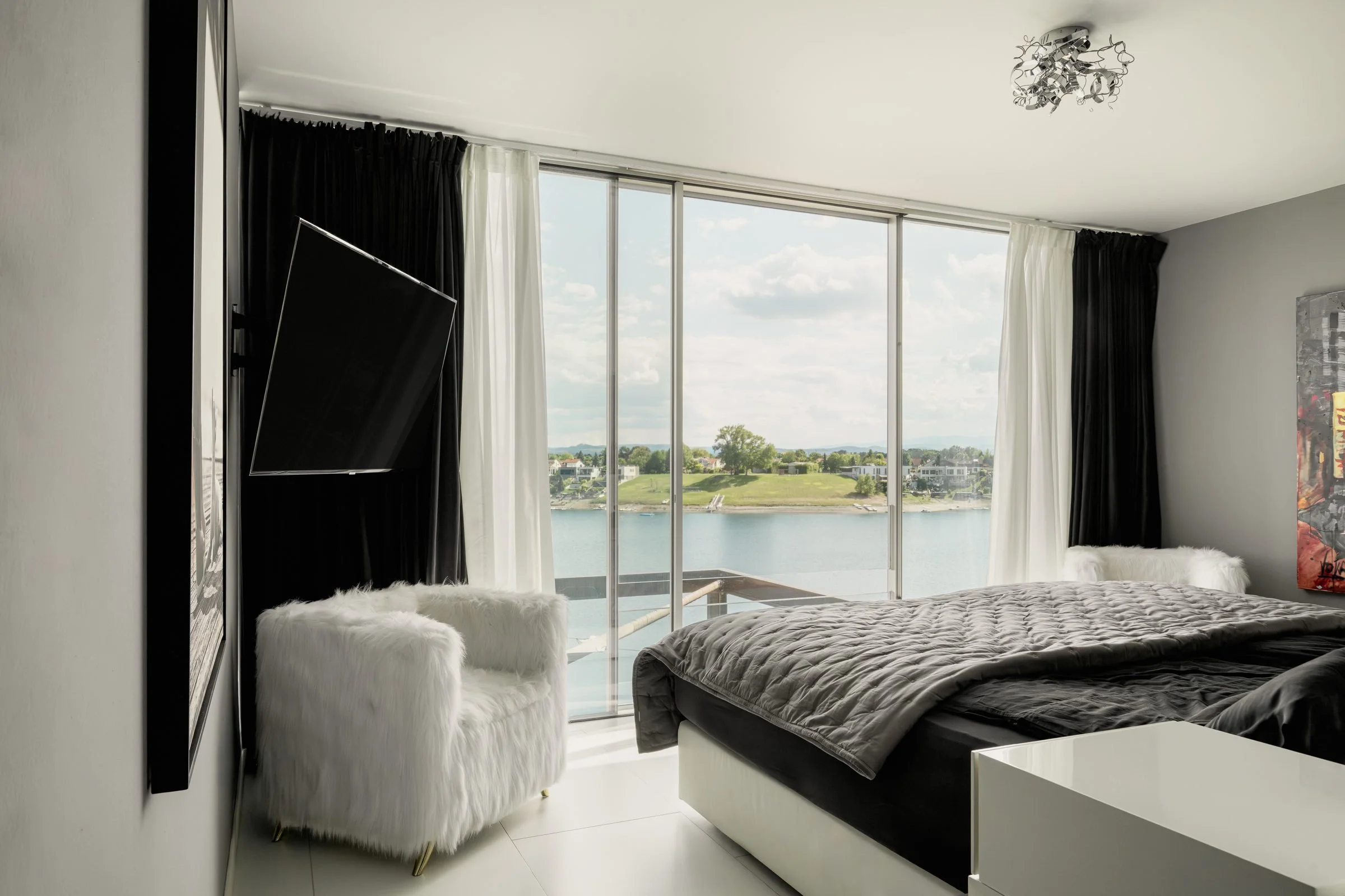 Schlafzimmer mit raumhoher Verglasung zum See