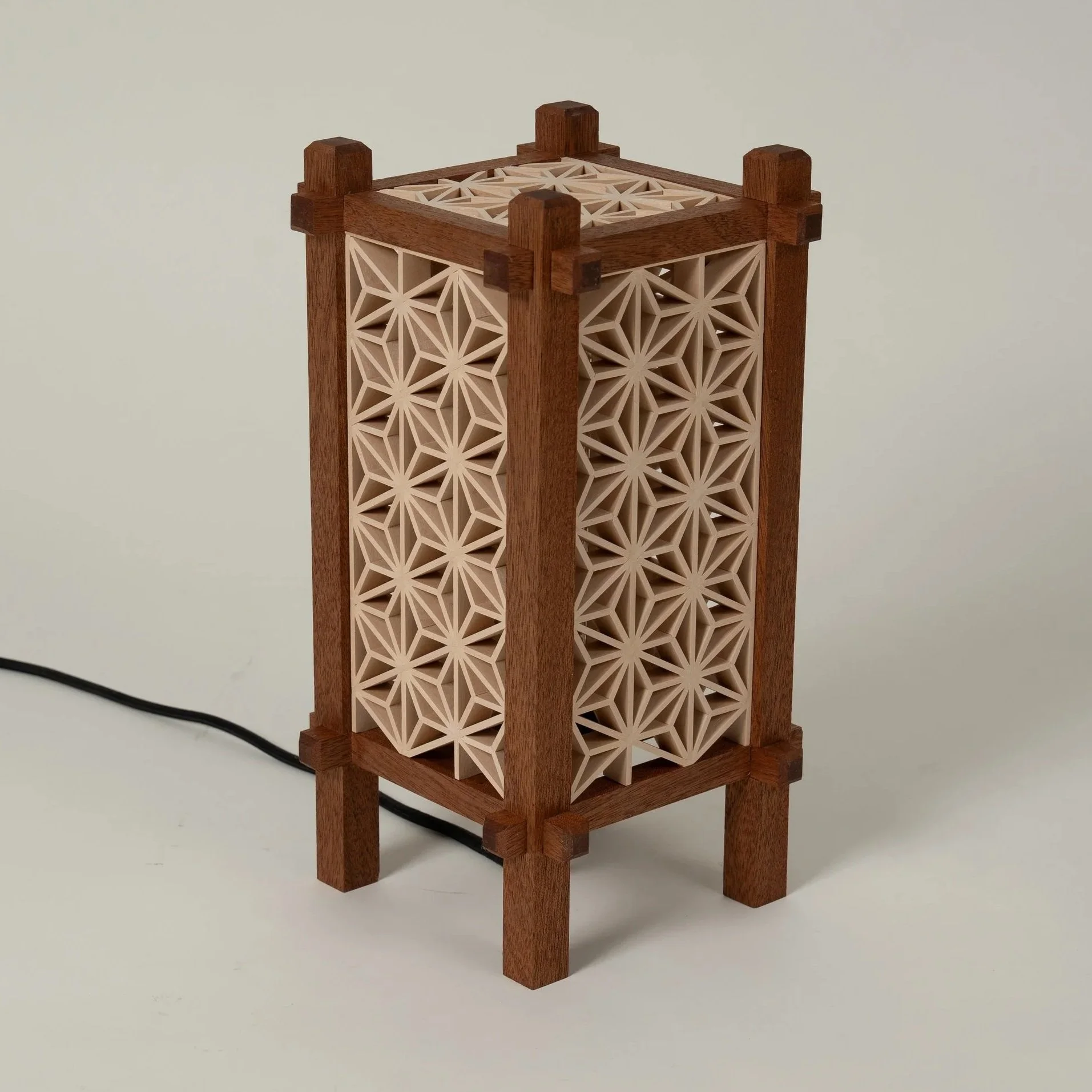 Yoake-tafellamp met houten frame en geometrische Kumiko-panelen, gefotografeerd op een lichte achtergrond.