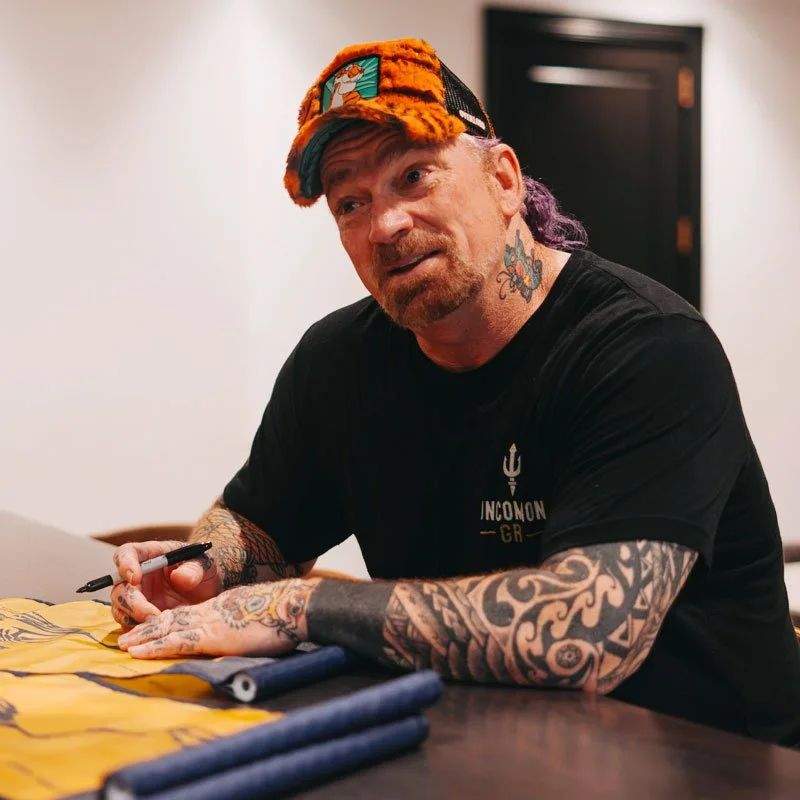 Navy SEAL Darren McBurnett signs  pin flags during an Uncommon Grit SEAL Foundation golf outing.
