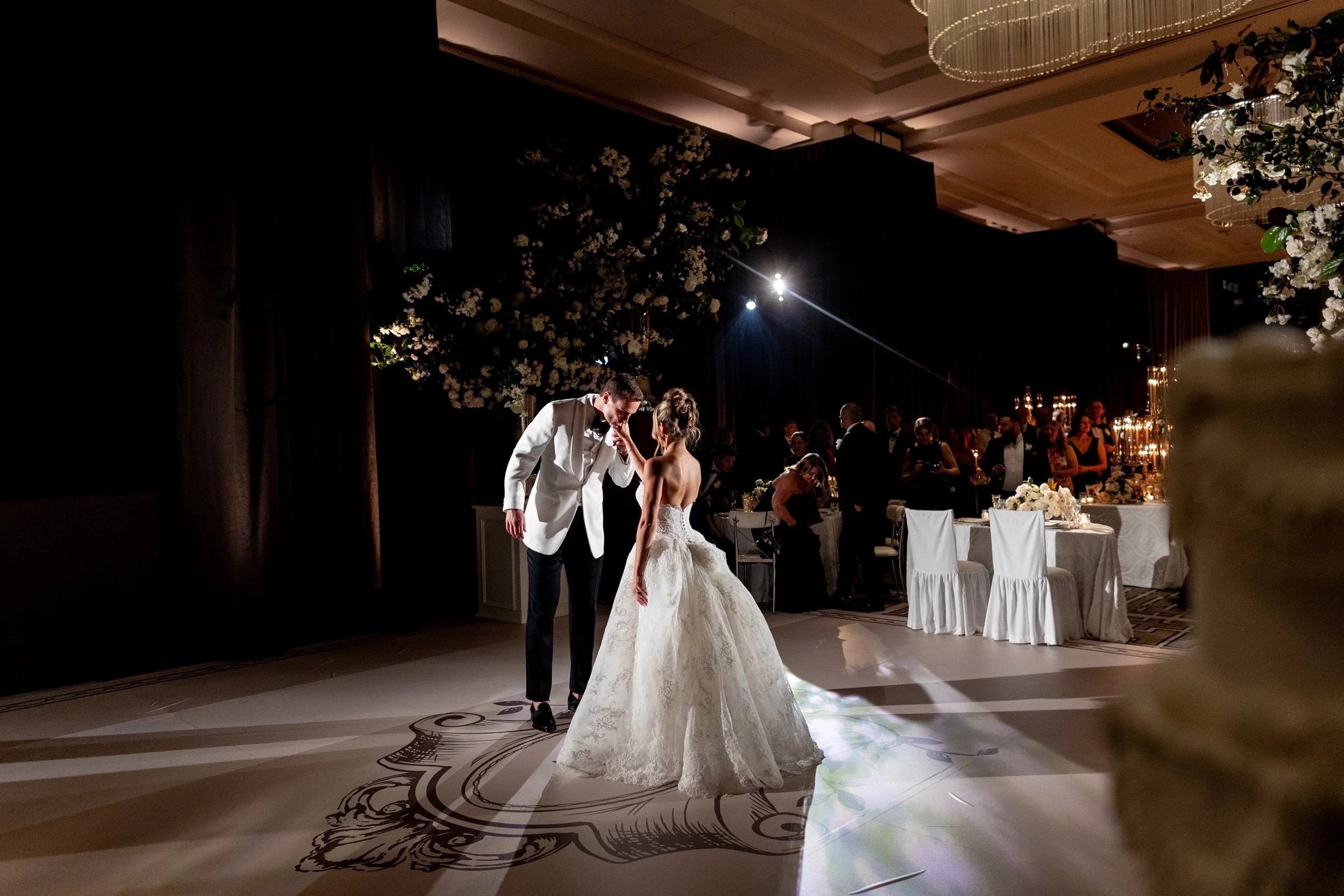 Bride and groom dancing at their evening reception with guests gathered around the floor