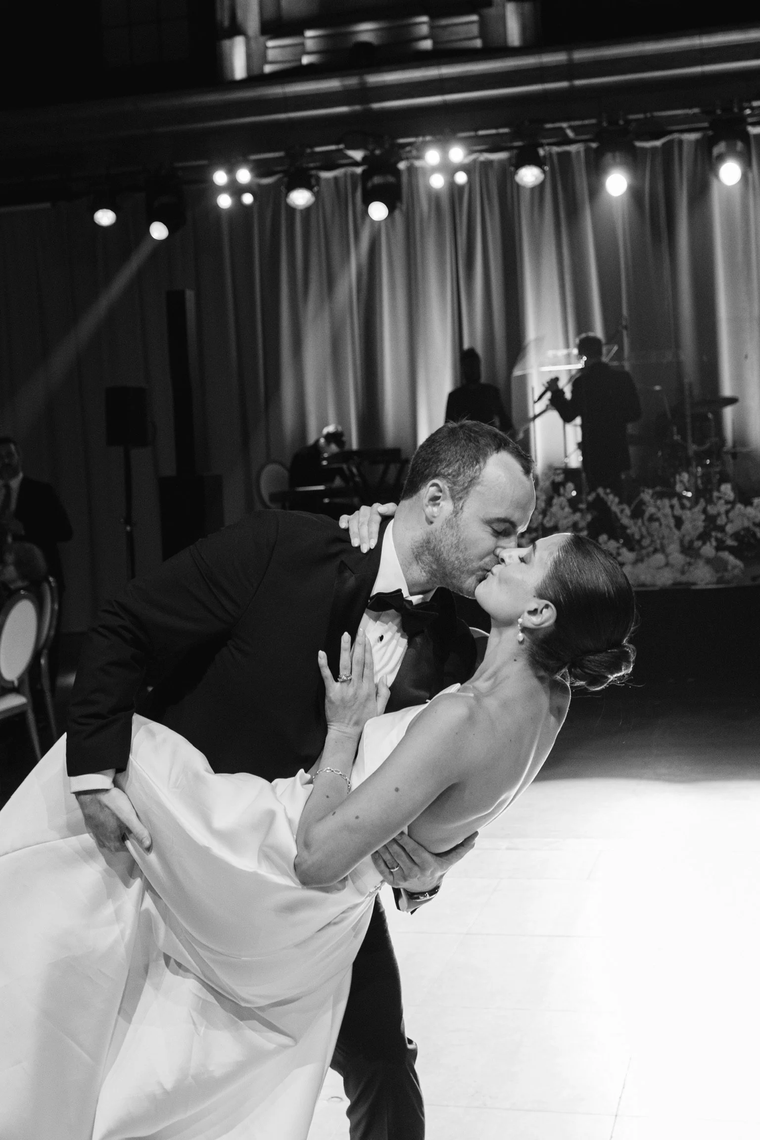 Black-and-white close-up of a groom kissing his bride during a wedding dance dip
