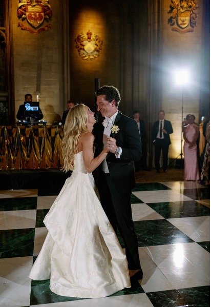 Bride and groom holding each other during their reception dance in a warmly lit ballroom
