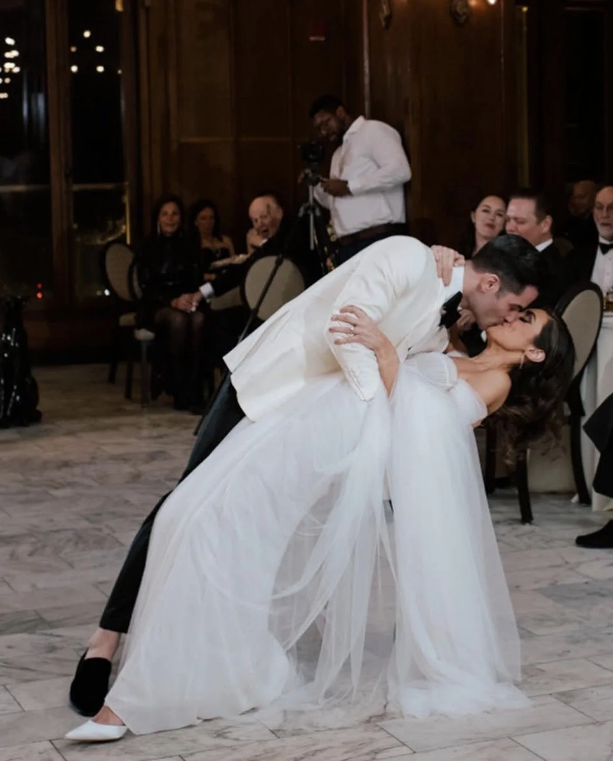 Groom dipping and kissing his bride at their indoor wedding reception