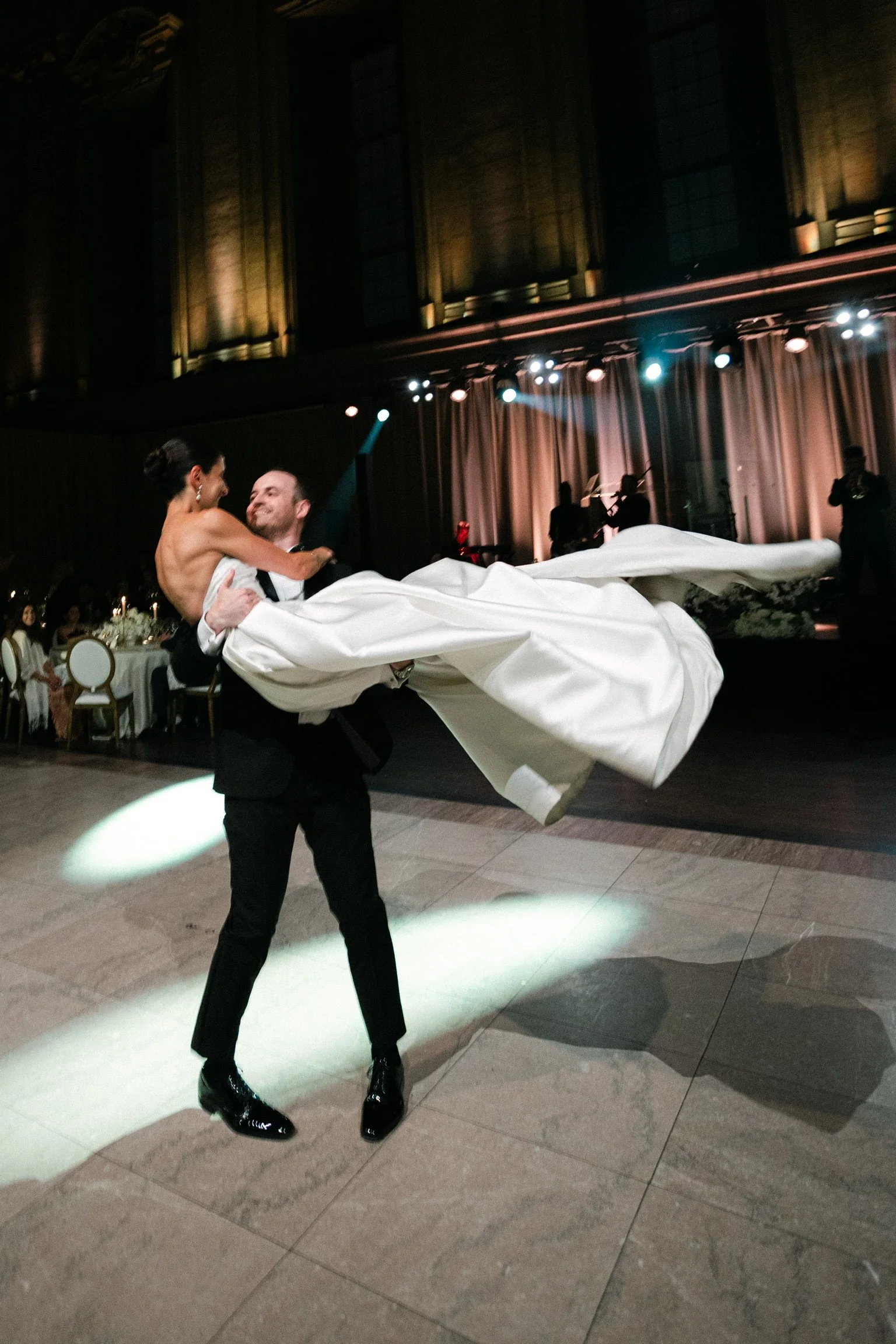 Groom lifting his bride as her white wedding dress sweeps across the dance floor