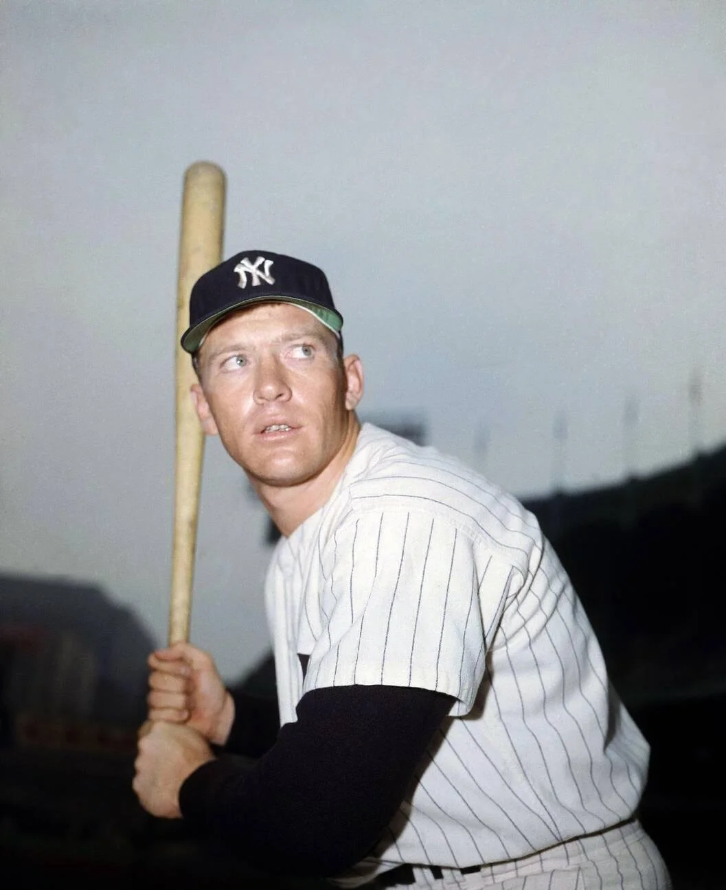 Mickey Mantle posing with a baseball bat in his New York Yankees uniform in 1957.