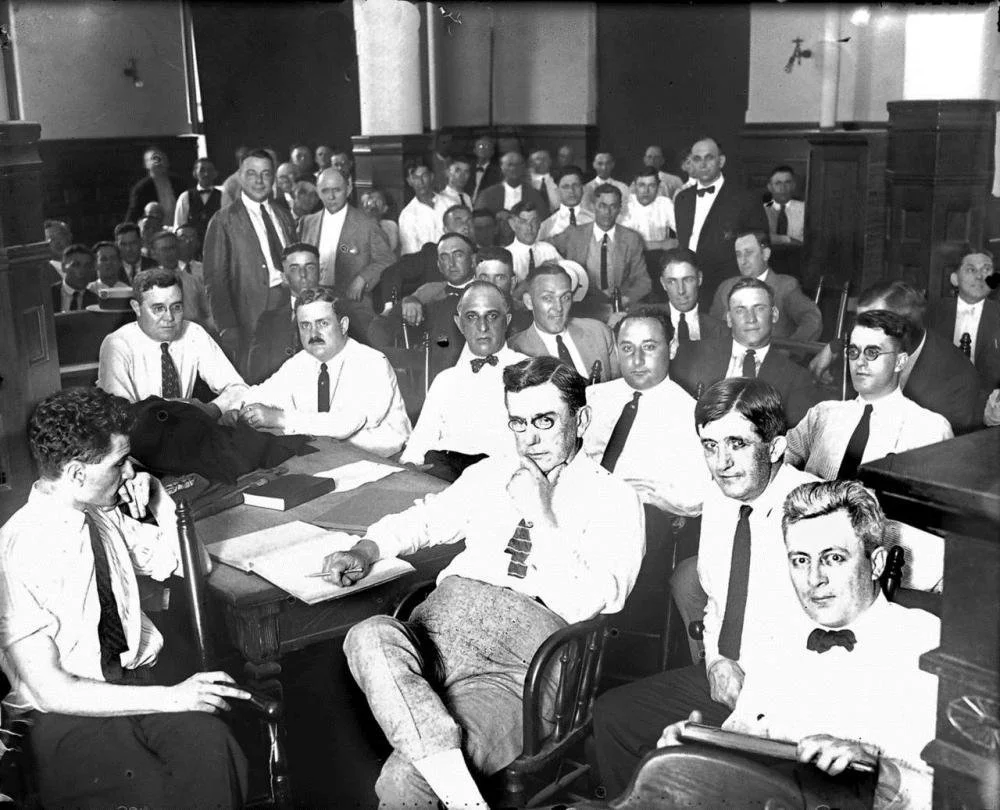 Chicago White Sox players accused in the Black Sox scandal sit with their attorneys during the 1921 trial; Shoeless Joe Jackson is seated towards the center of image.