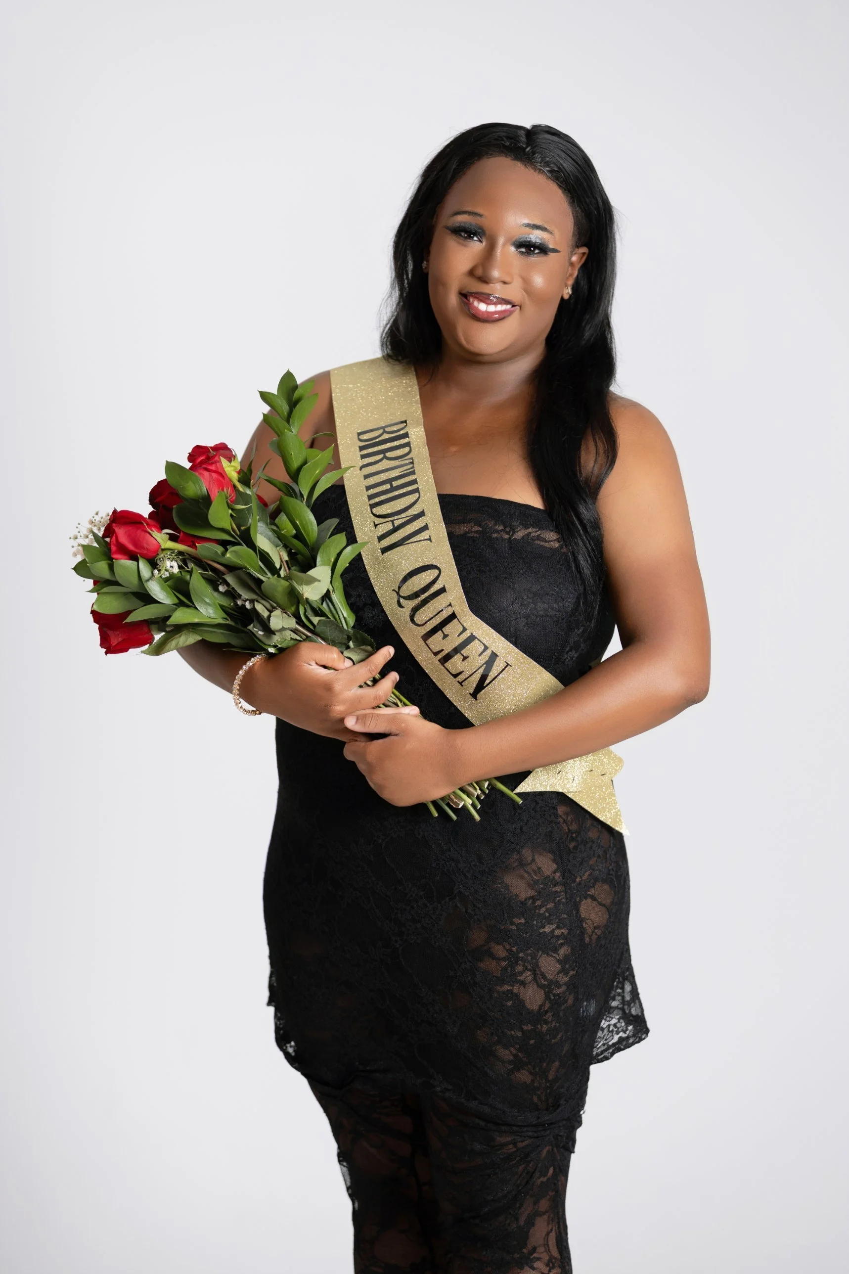 Birthday portrait session at The Social House studio in Myrtle Beach: a woman in a black lace dress and gold Birthday Queen sash holding red roses.