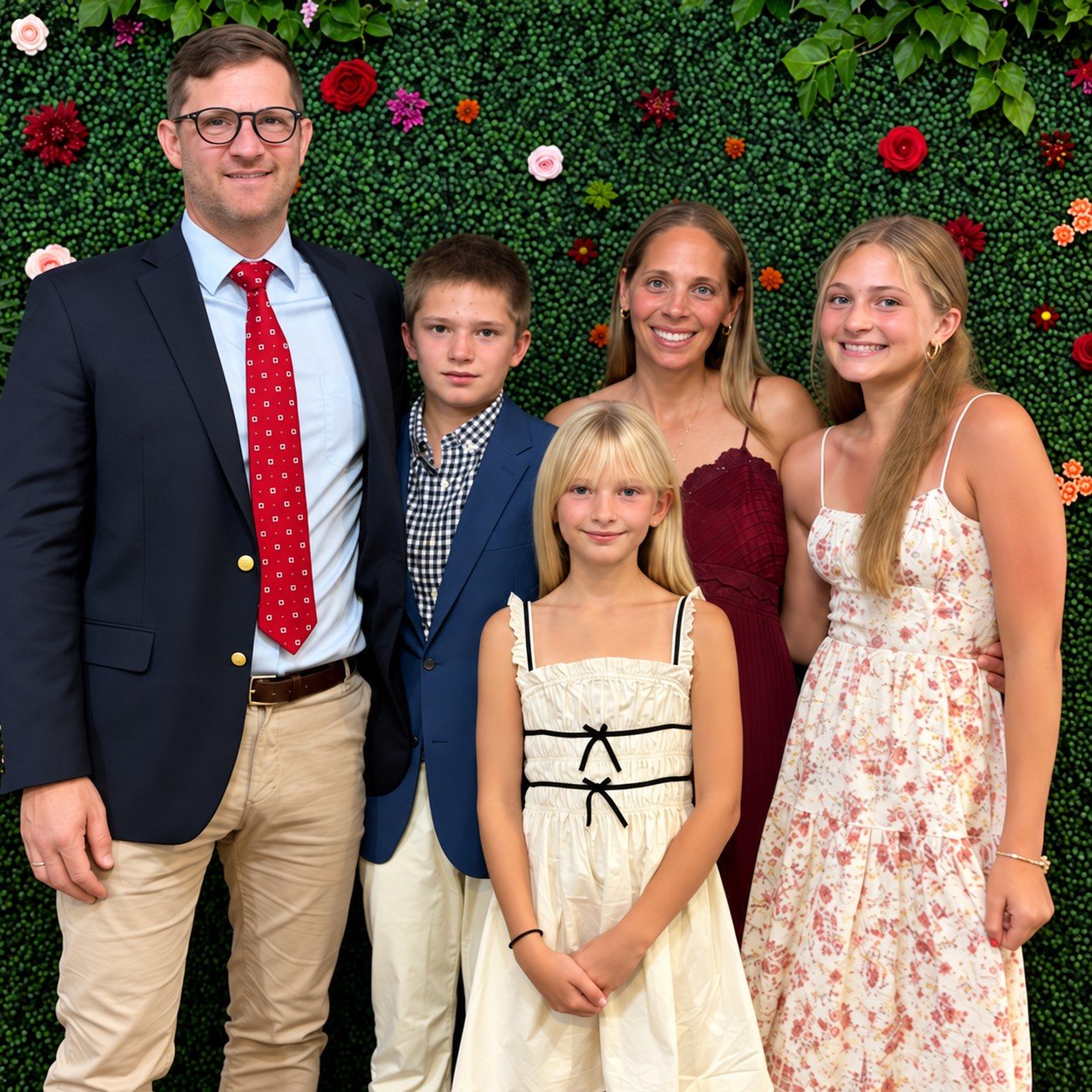 Nick with his family, dressed up in front of a flower wall
