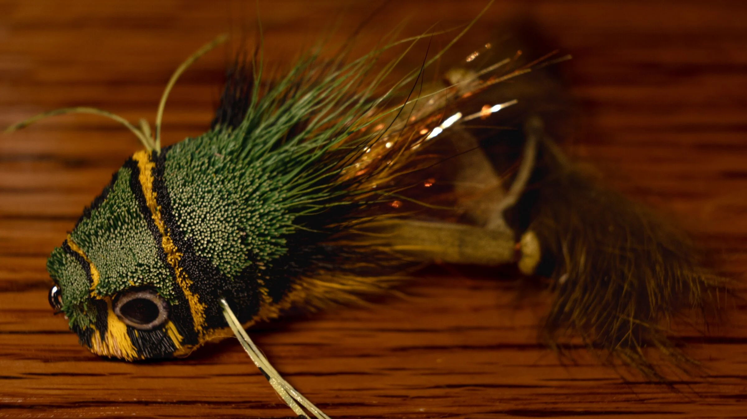 From the Bench. Green and yellow deer-hair frog fly on a wooden tying desk.