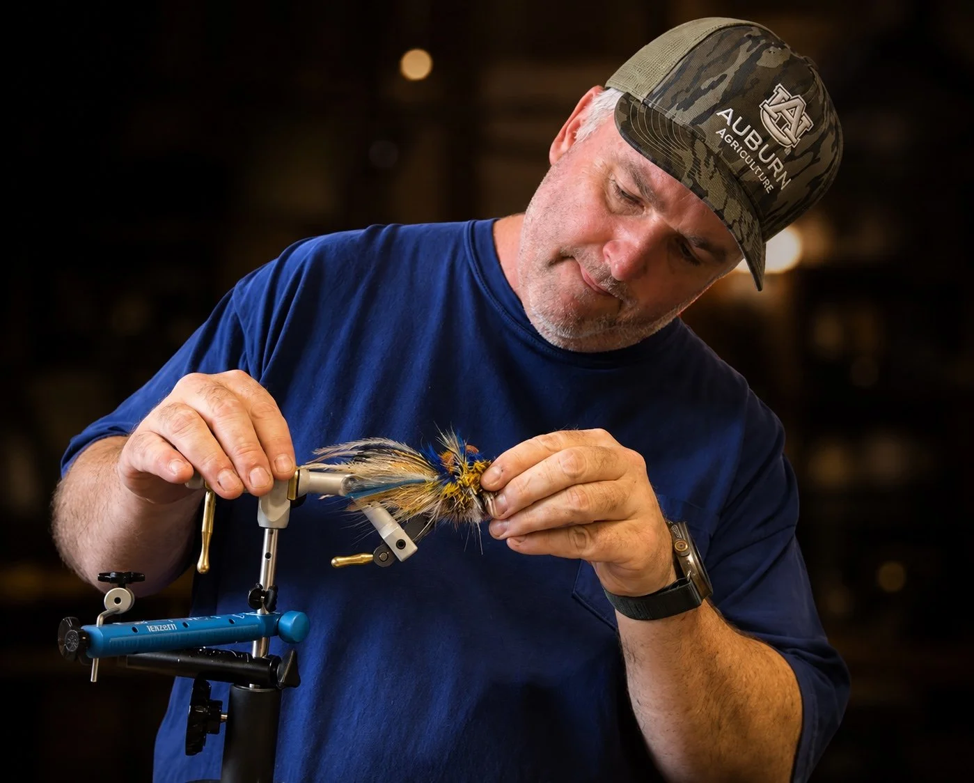 Lee H. Blanton handling a deer-hair fly at his tying bench.