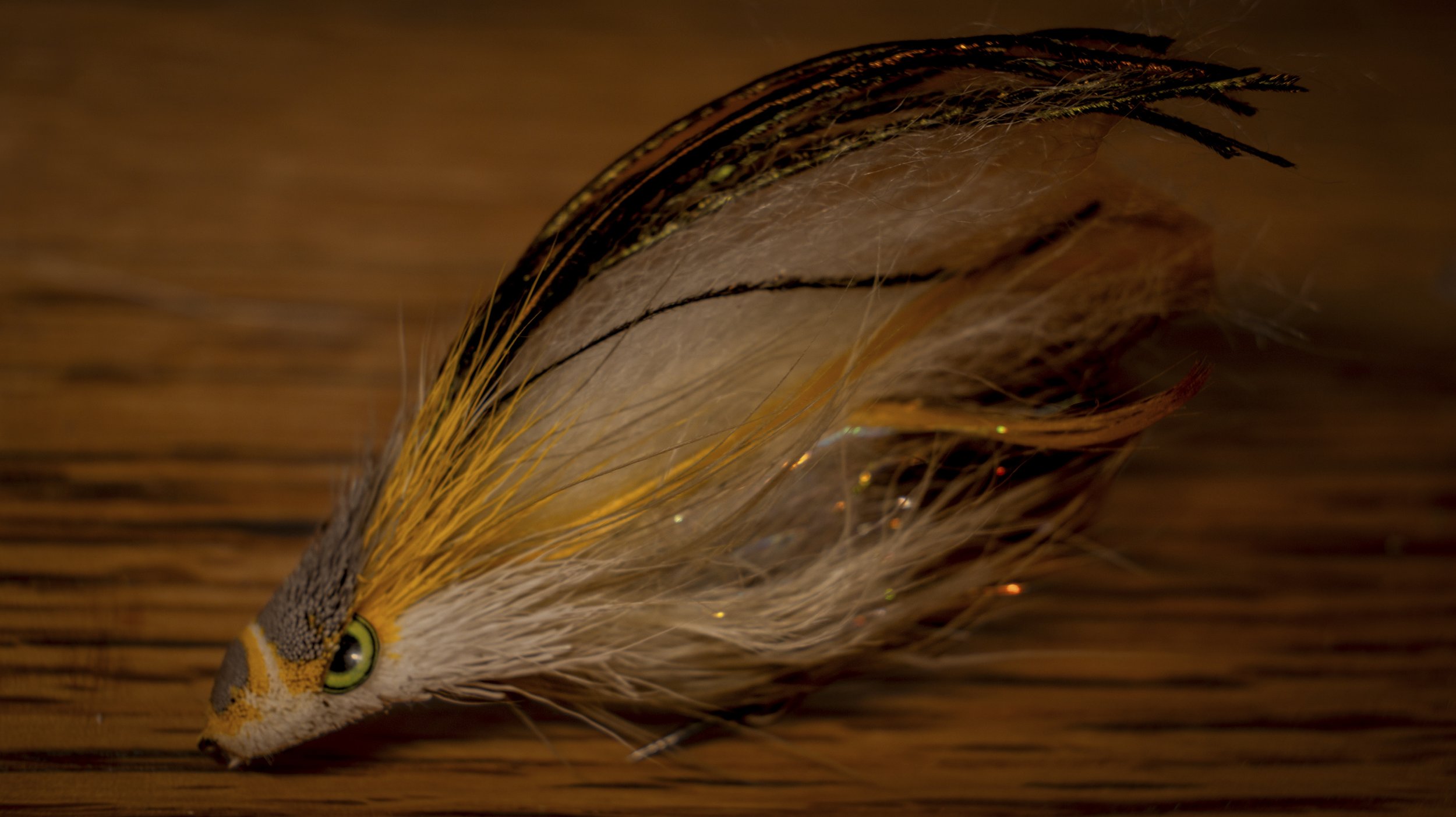 Instruction. Leased Gilt fly with a clipped deer-hair wedge head, green eye and dark feather overwing.