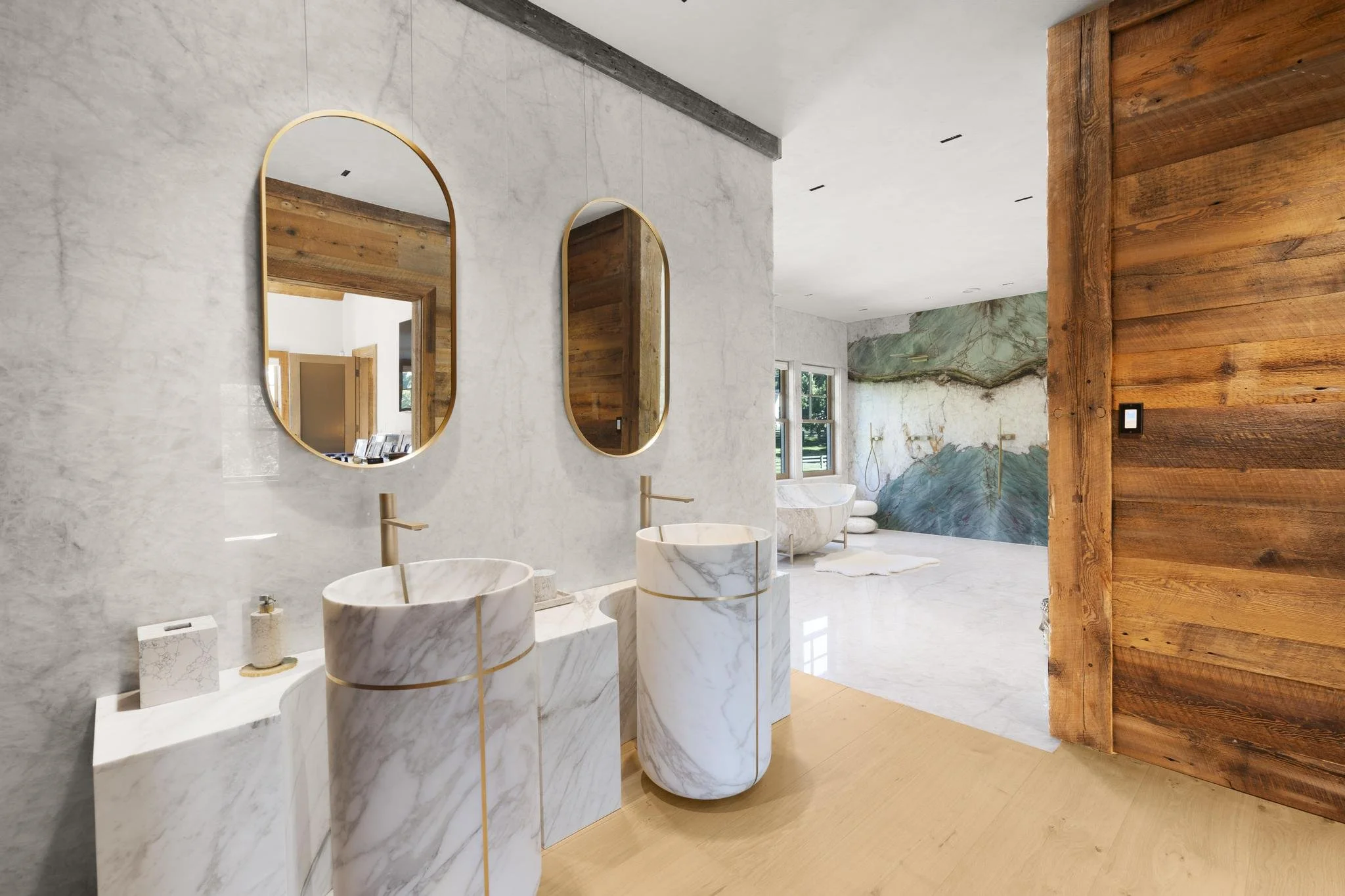 Modern bathroom with marble sinks, mirror, wood accents, and a textured wall with mountain-like pattern.