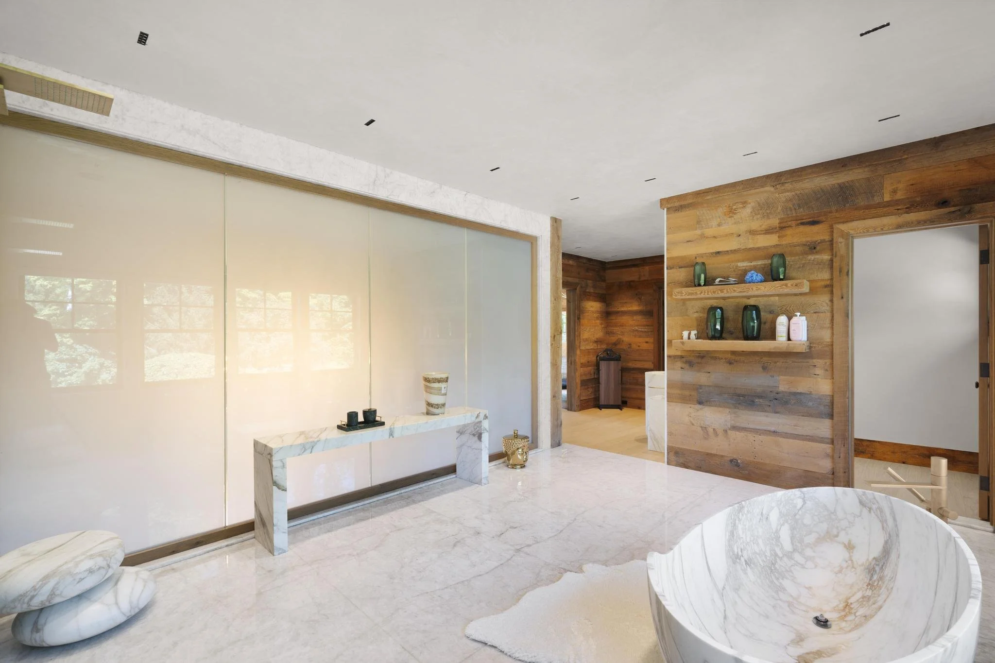Living room with white marble fireplace, wooden wall accent, beige sliding doors, and modern decor including vases and bottles.