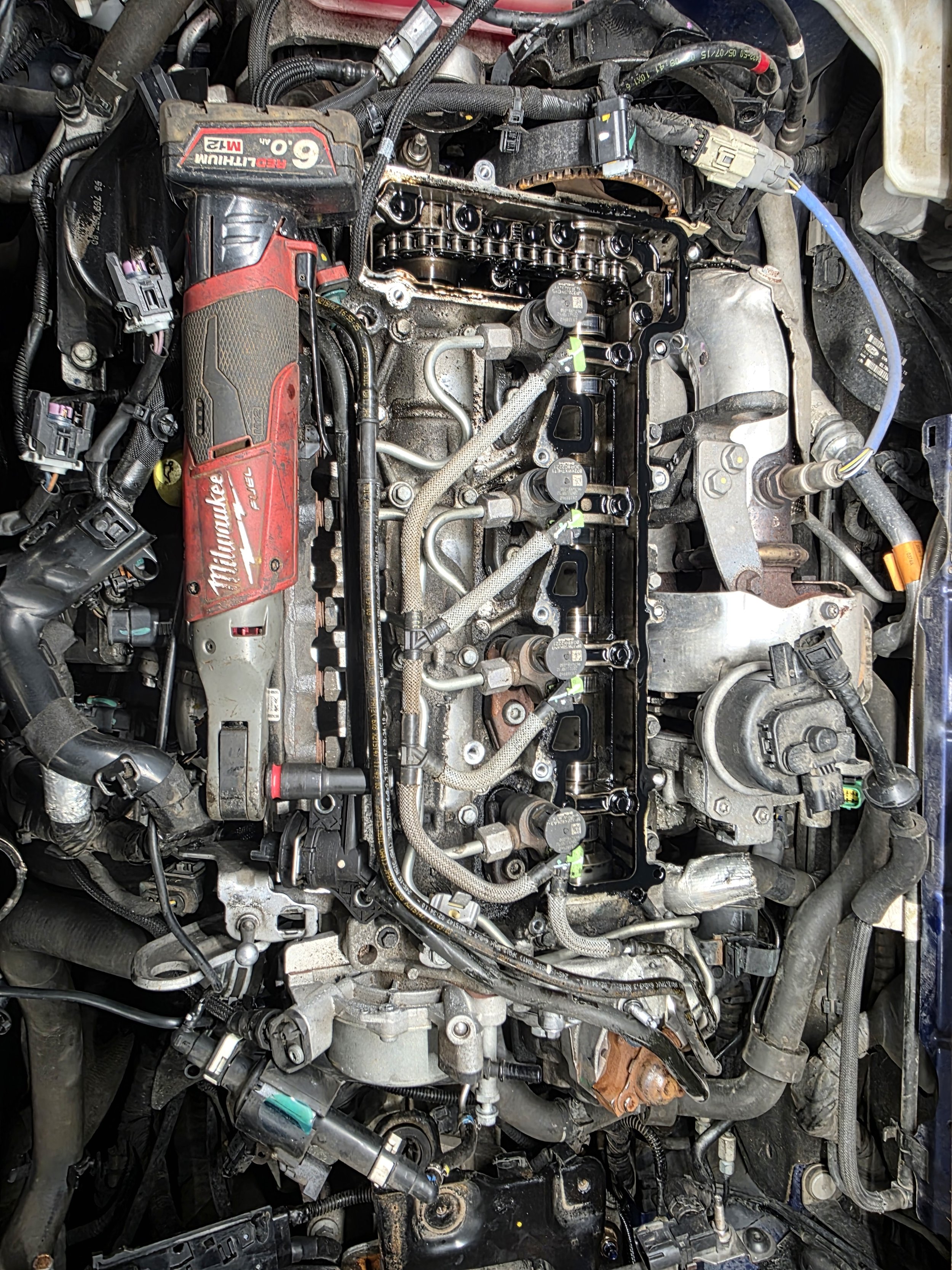 The image shows the internal engine components of a vehicle, including valves, pistons, and various mechanical and electrical parts.