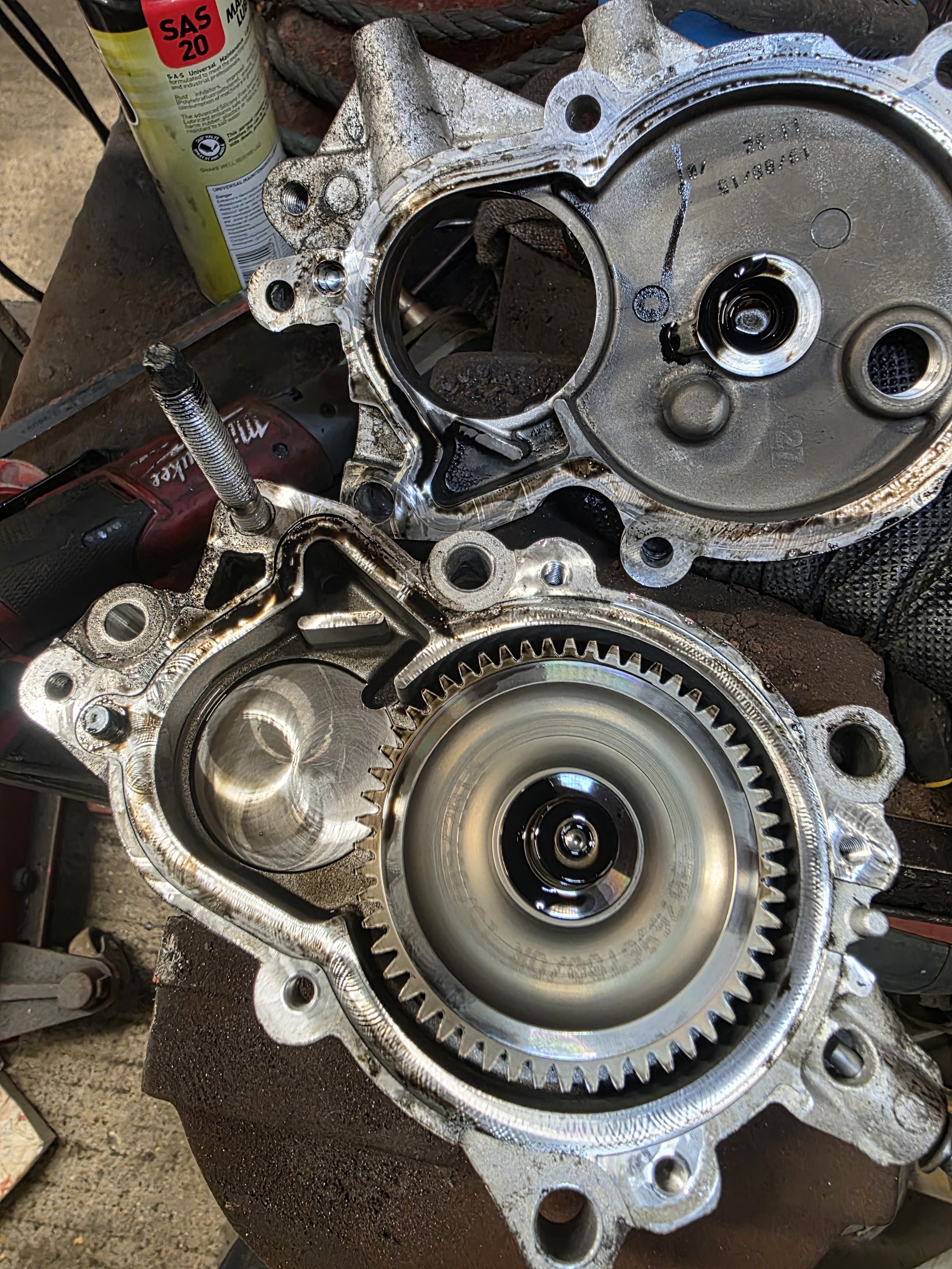 Close-up of a disassembled engine diesel fuel pump with gears and metal components, some oil and grease, on a work table.