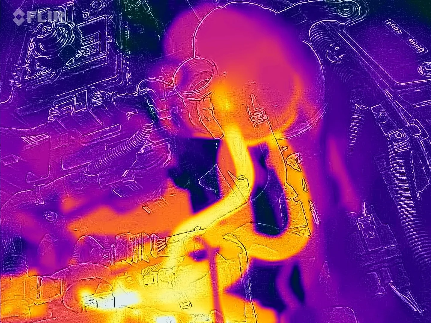 Thermal image of an engine bay showing various mechanical components, with heat signatures in yellow, orange, and purple hues.