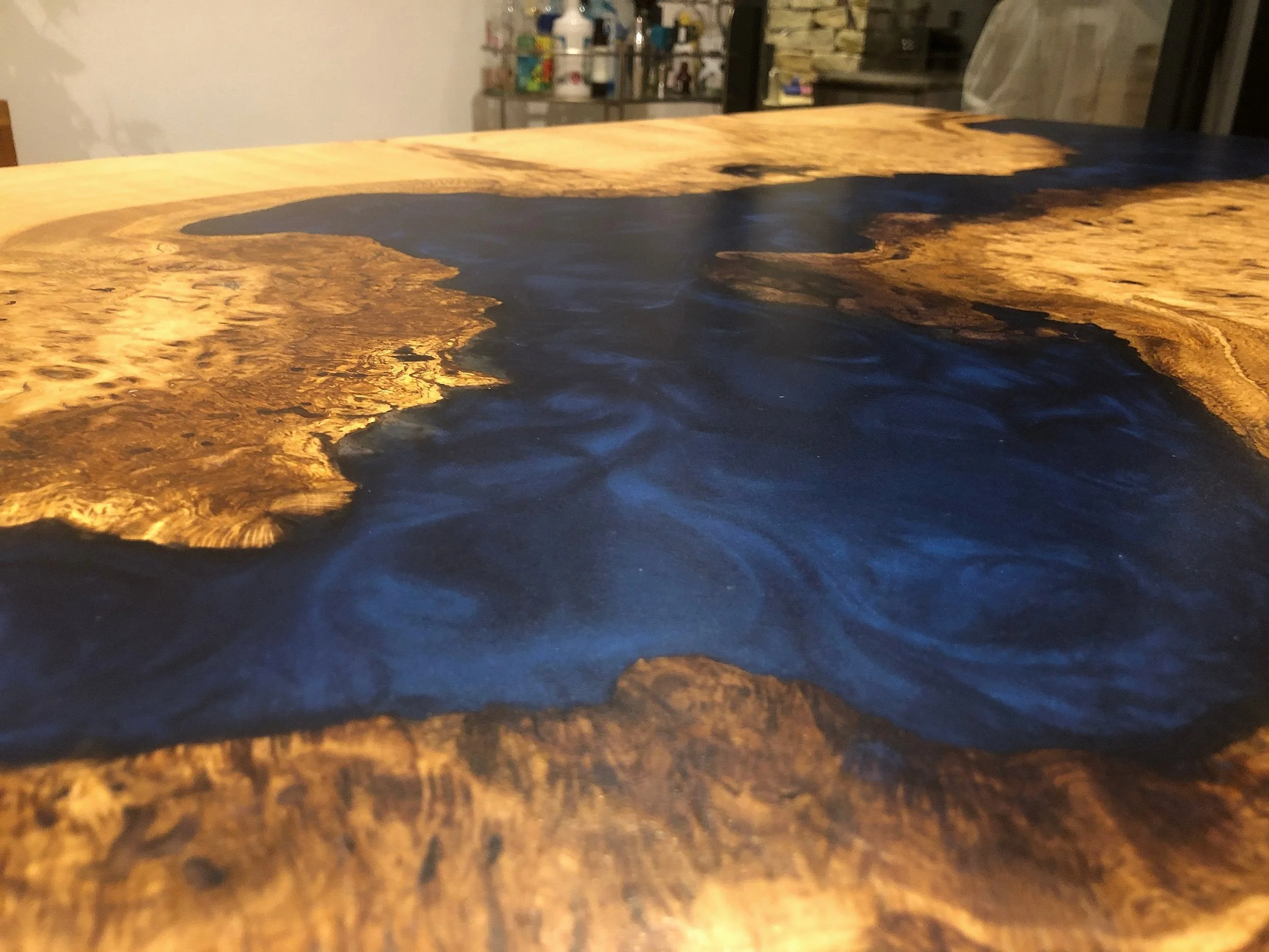 Dark blue epoxy resin and wood river table close up showing swirl details in the resin