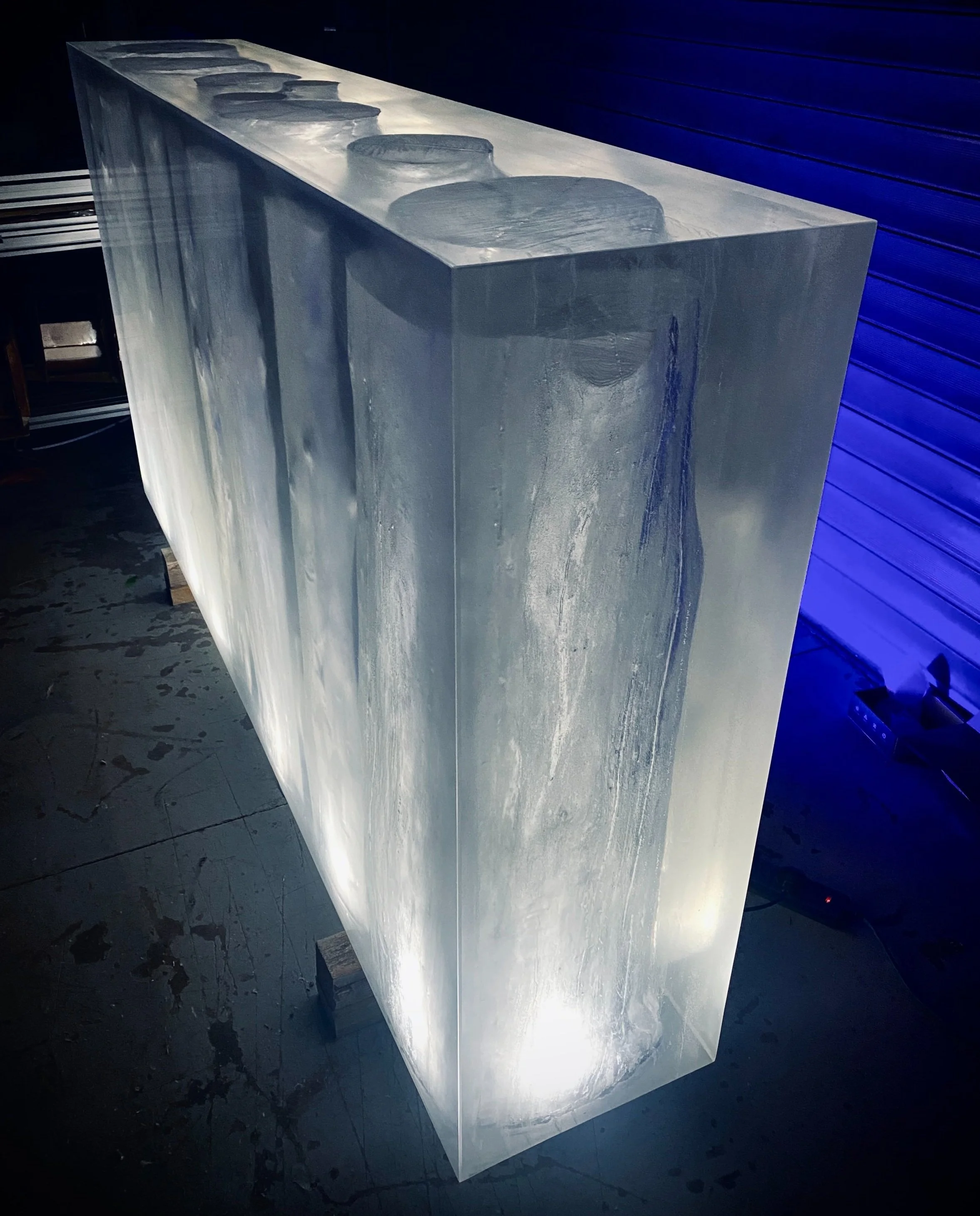 Angled view of clear epoxy resin block with hollow log shaped sections showing depth