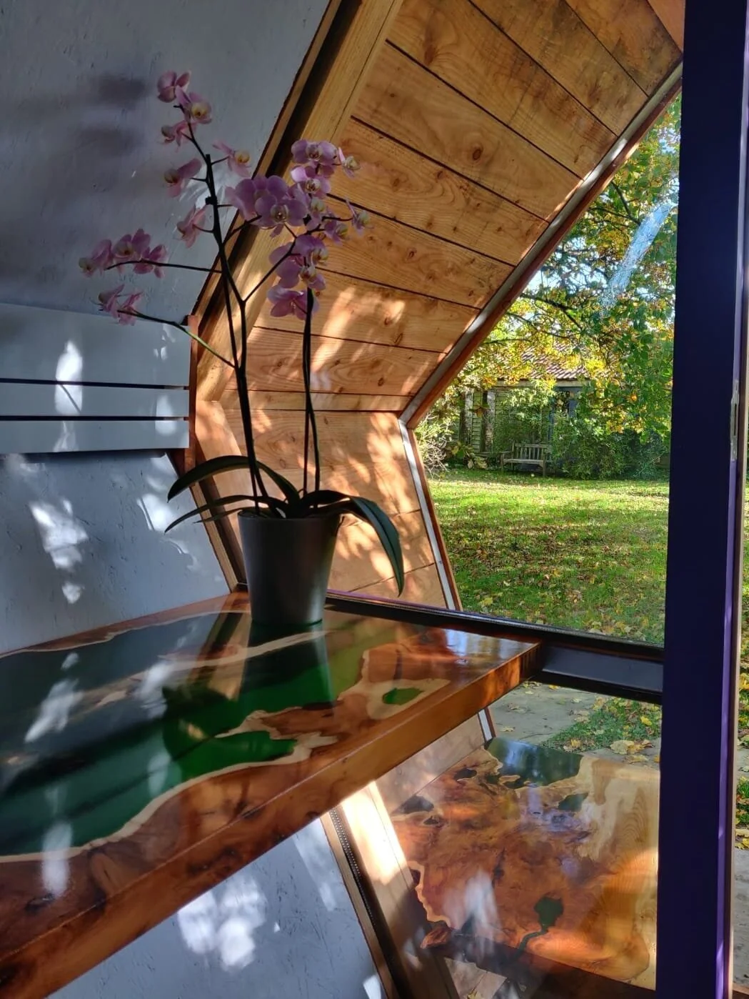 emerald green epoxy resin desk with plant against a window in a garden office 