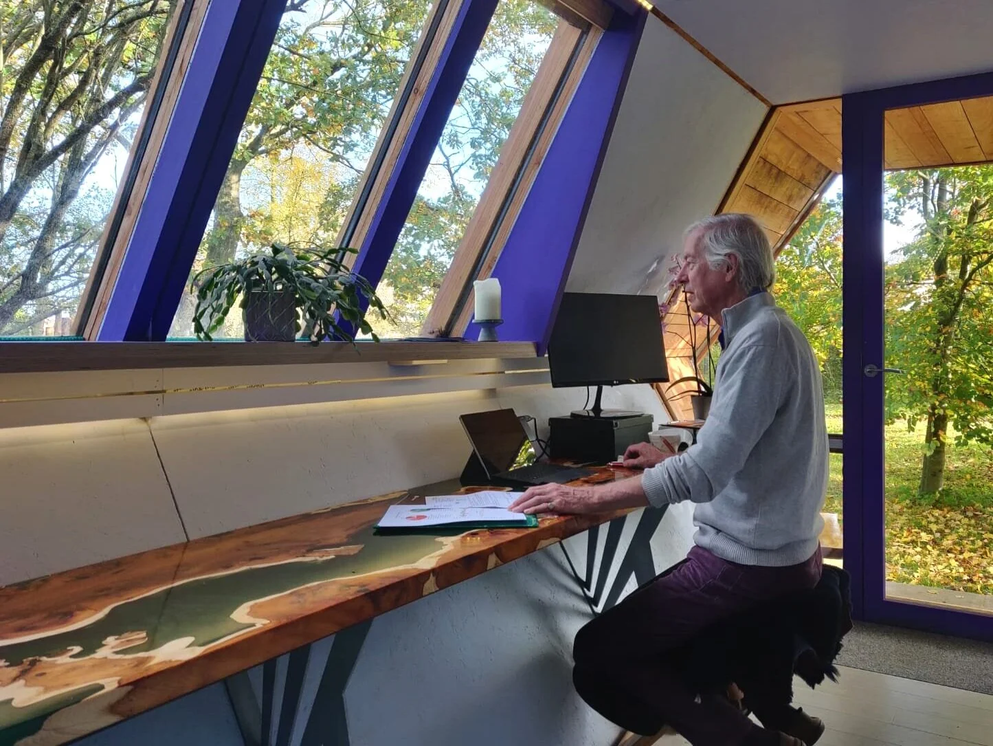 Epoxy resin and yew desk in a garden office with man sat at desk working