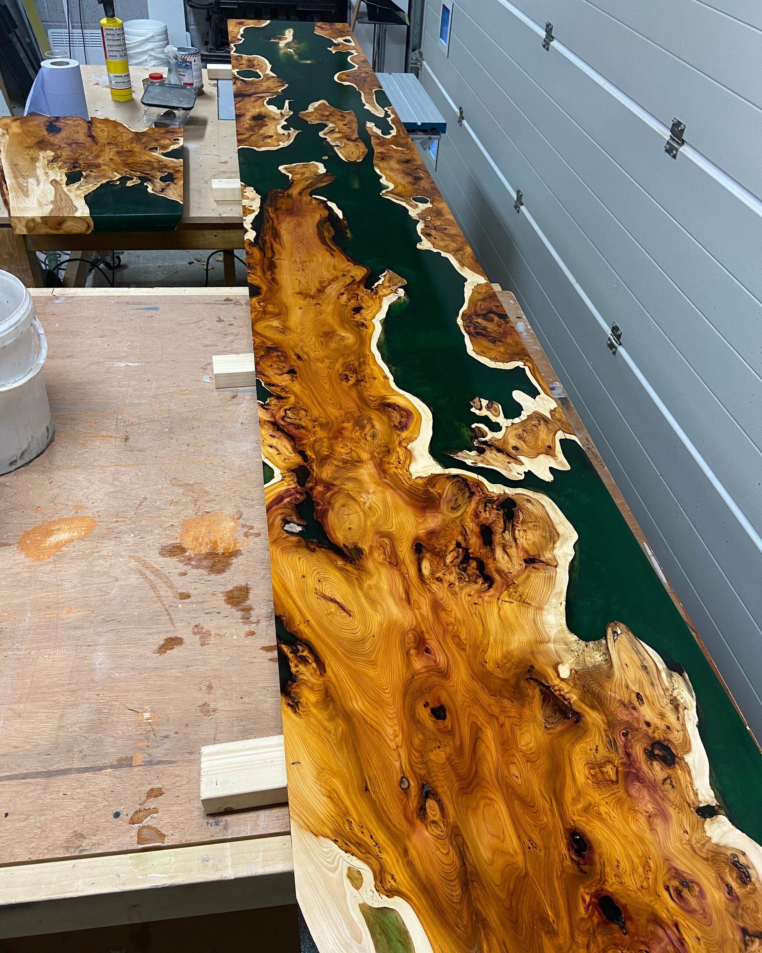 epoxy resin river table desk with green resin and english yew in workshop sat on workbench