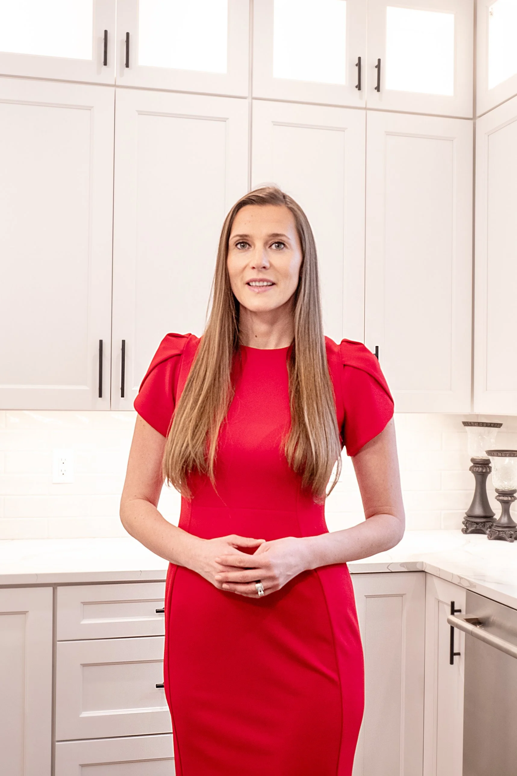 Woman in a red dress standing in a bright white kitchen