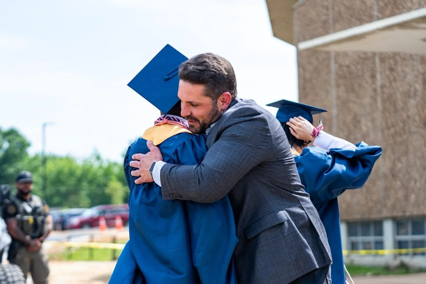 Mayor Scott Conger hugging a JMCSS high school graduate in a blue cap and gown