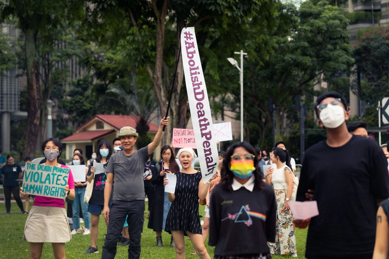 A group of people protesting outdoors, holding signs advocating for human rights and reproductive rights, with many wearing masks.