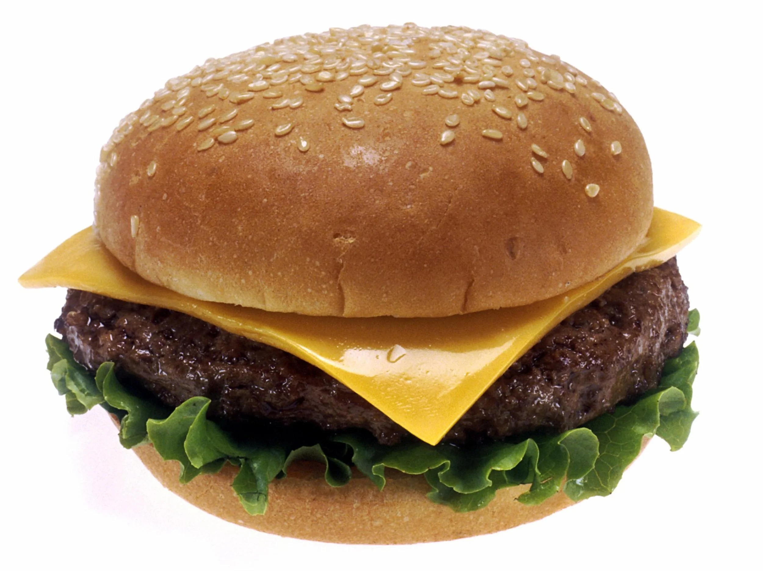 Close-up of a cheeseburger with lettuce, a beef patty, cheddar cheese, and a sesame seed bun.